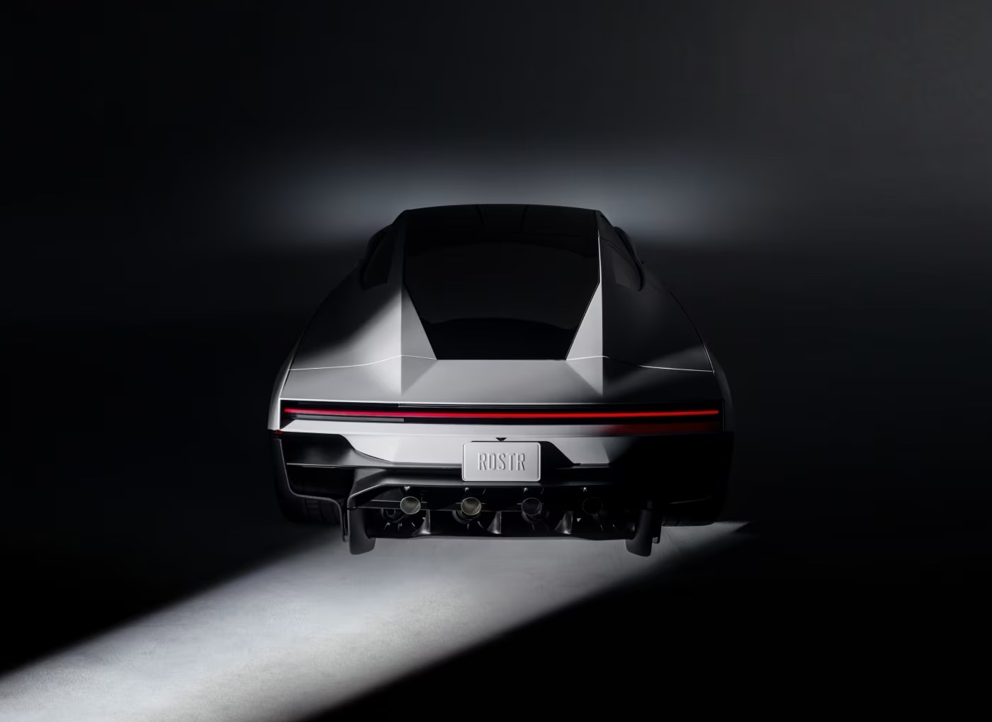 New Tesla Roadster from the rear, with one full-length red taillight across the tail and exposed nozzles and fans below the number plate